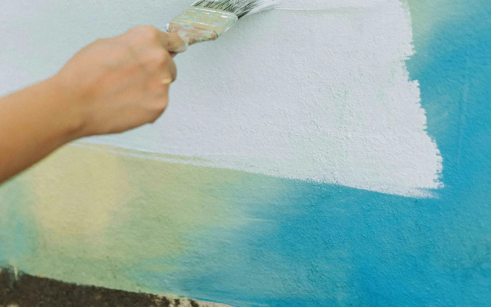 Person painting a white wall with a roller.